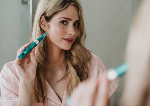 Woman holding  Dr Pen A6S Microneedling pen to her face