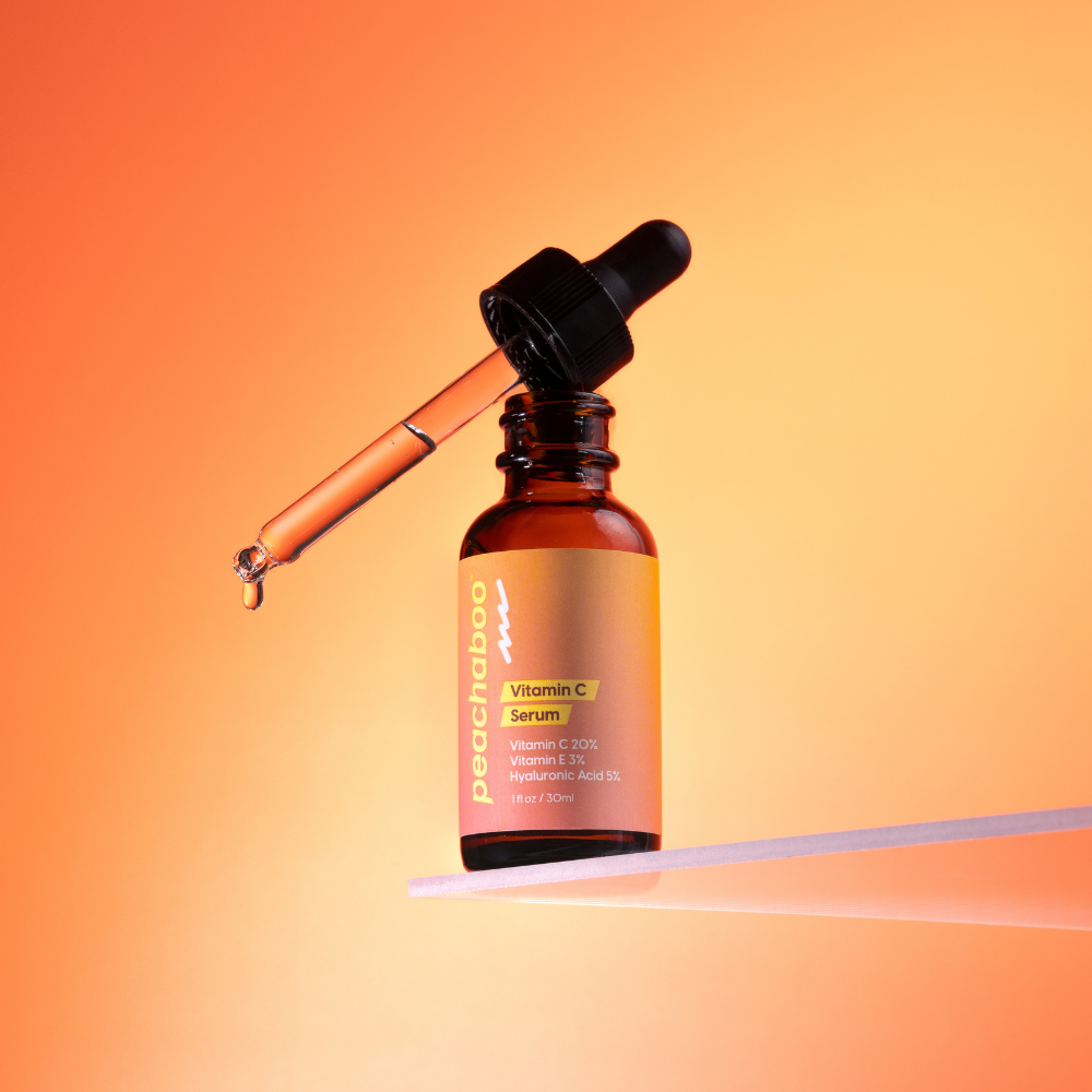 Vitamin C serum bottle with dropper on an orange gradient background