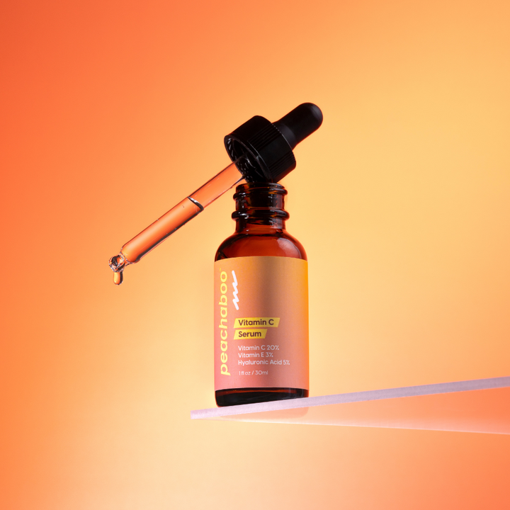 Vitamin C serum bottle with dropper on an orange gradient background