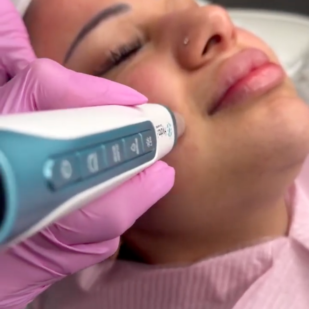 Dr. Pen H6 microneedling pen being used during a facial treatment on a client's cheek.